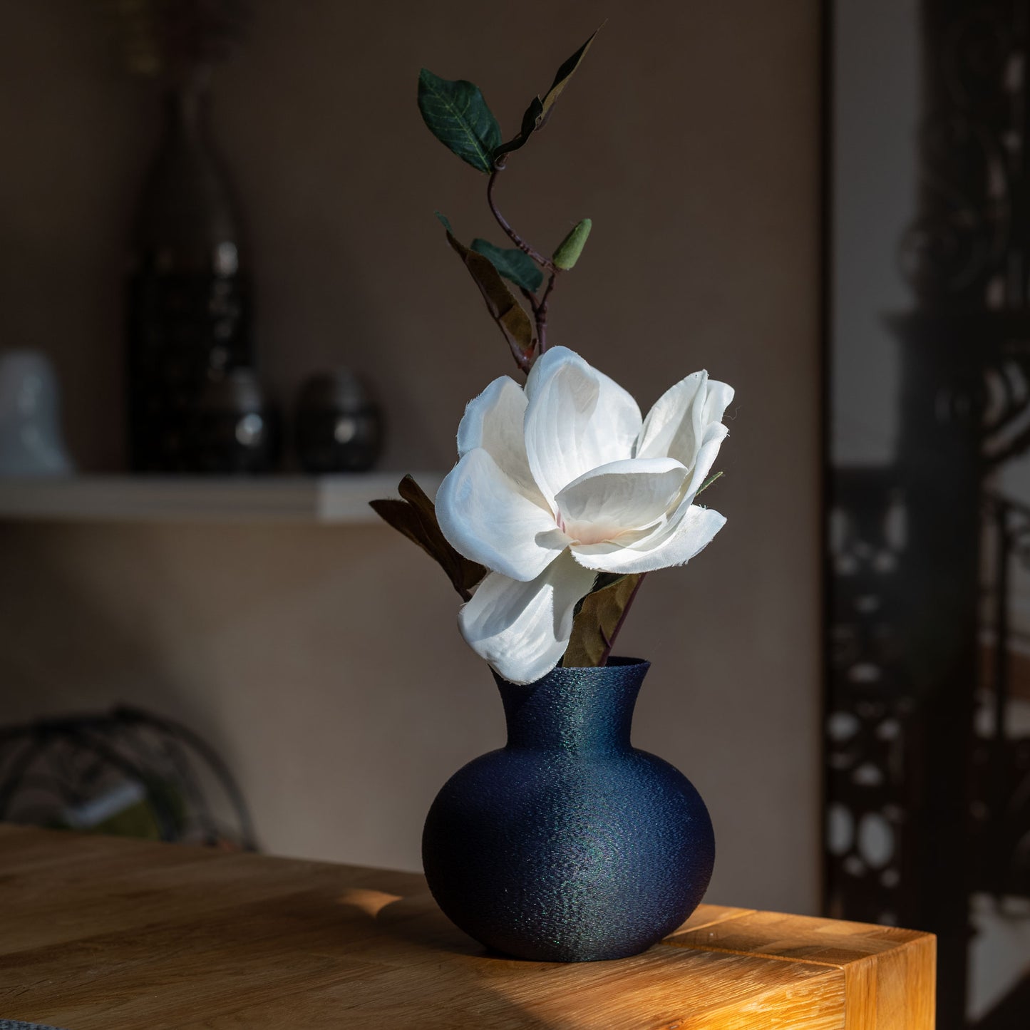 changierendem Dunkelblaue nachhaltige Vase aus PLA mit matter, leicht strukturierter Oberfläche, dekorativ arrangiert mit einem Blume auf einem Tisch – stilvoll und umweltfreundlich.
