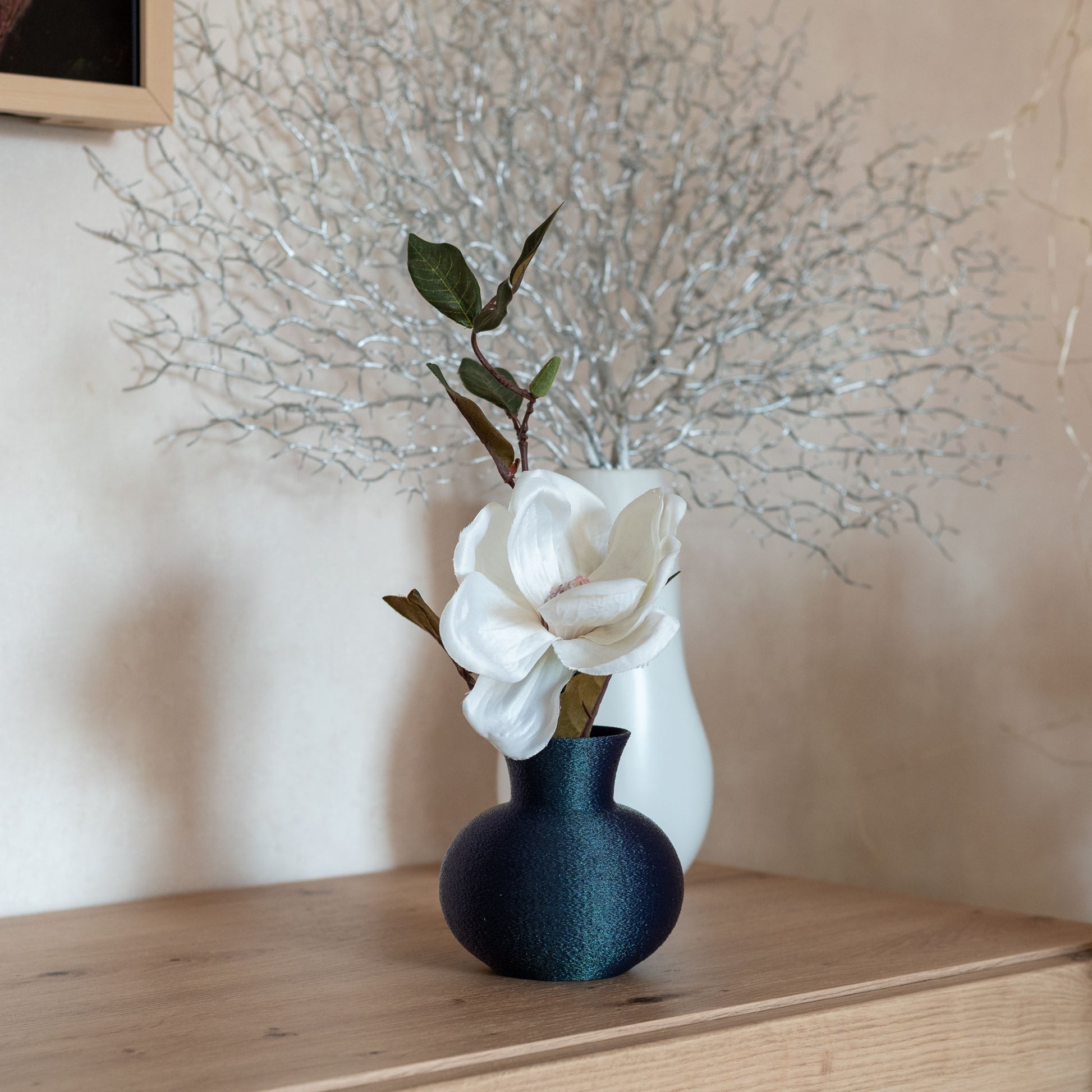 changierendem Dunkelblaue nachhaltige Vase aus PLA mit matter, leicht strukturierter Oberfläche, dekorativ arrangiert mit einem Blumer auf einem Sideboard – stilvoll und umweltfreundlich.