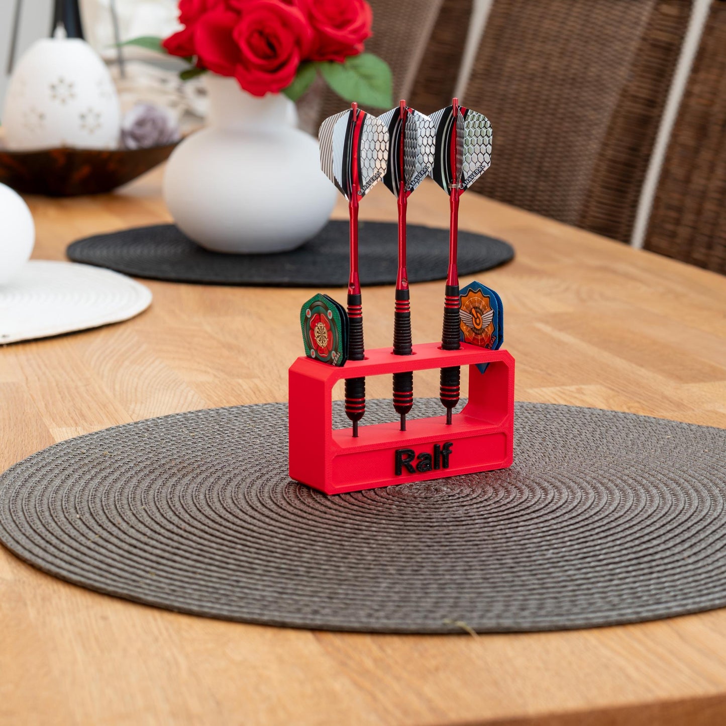 Roter 3D-gedruckter nachhaltiger Darthalter aus PLA mit drei Darts und dem Namen 'Ralf' auf einem Holztisch