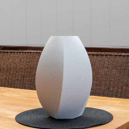 Modern designte Sechseck-Vase in hellgrauer Marmoroptik aus bruchfestem PLA – freistehend auf einem Holztisch.