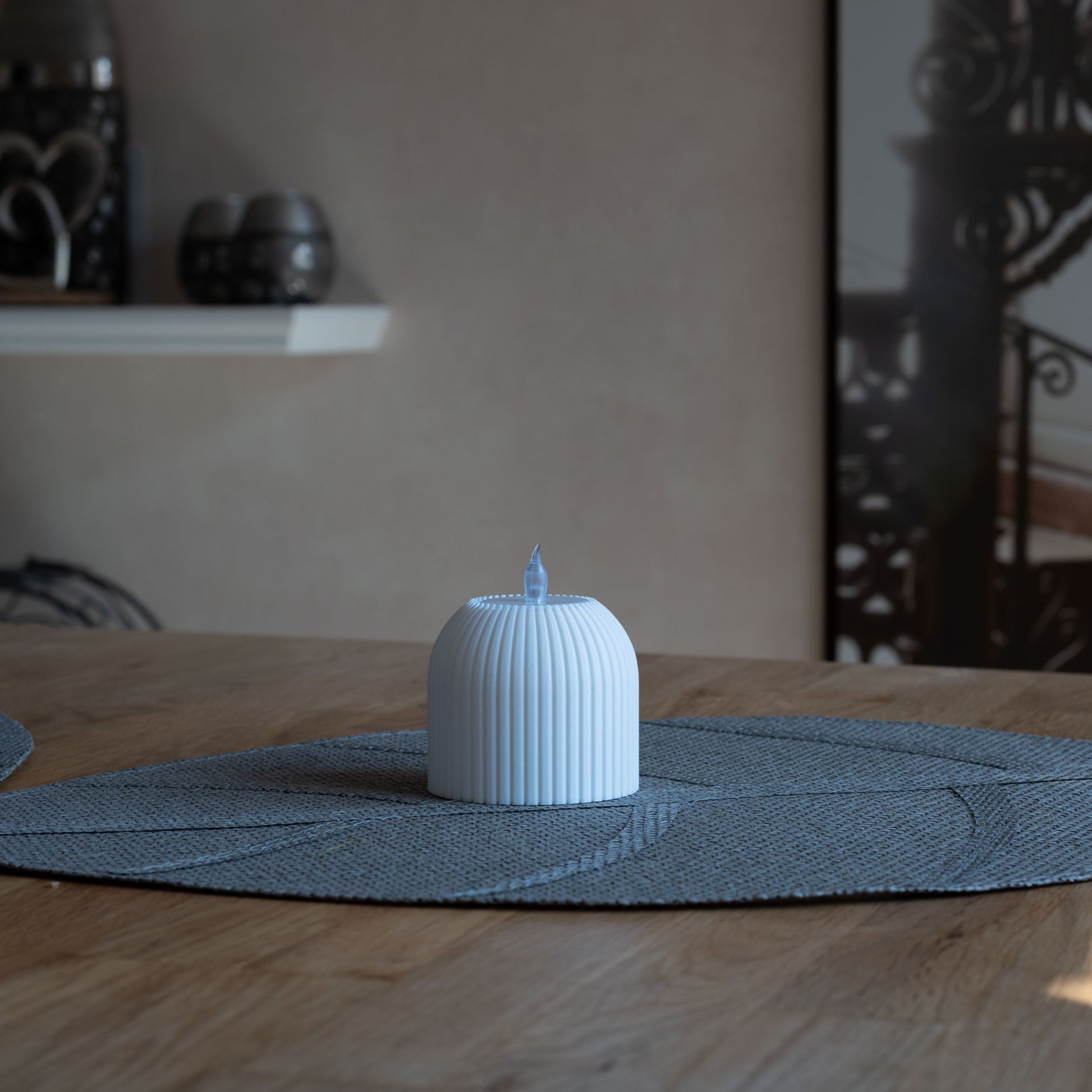 Nachhaltiges, weißes Teelicht mit vertikalen Rillen, 3D-gedruckt aus PLA, steht auf grauem Tischset
