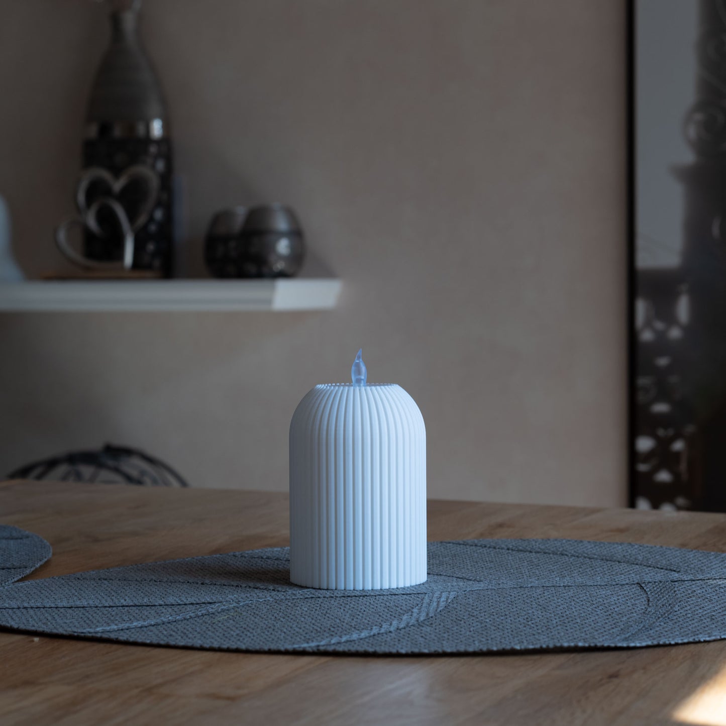 Nachhaltiges, weißes Teelicht mit vertikalen Rillen, 3D-gedruckt aus PLA, steht auf grauem Tischset