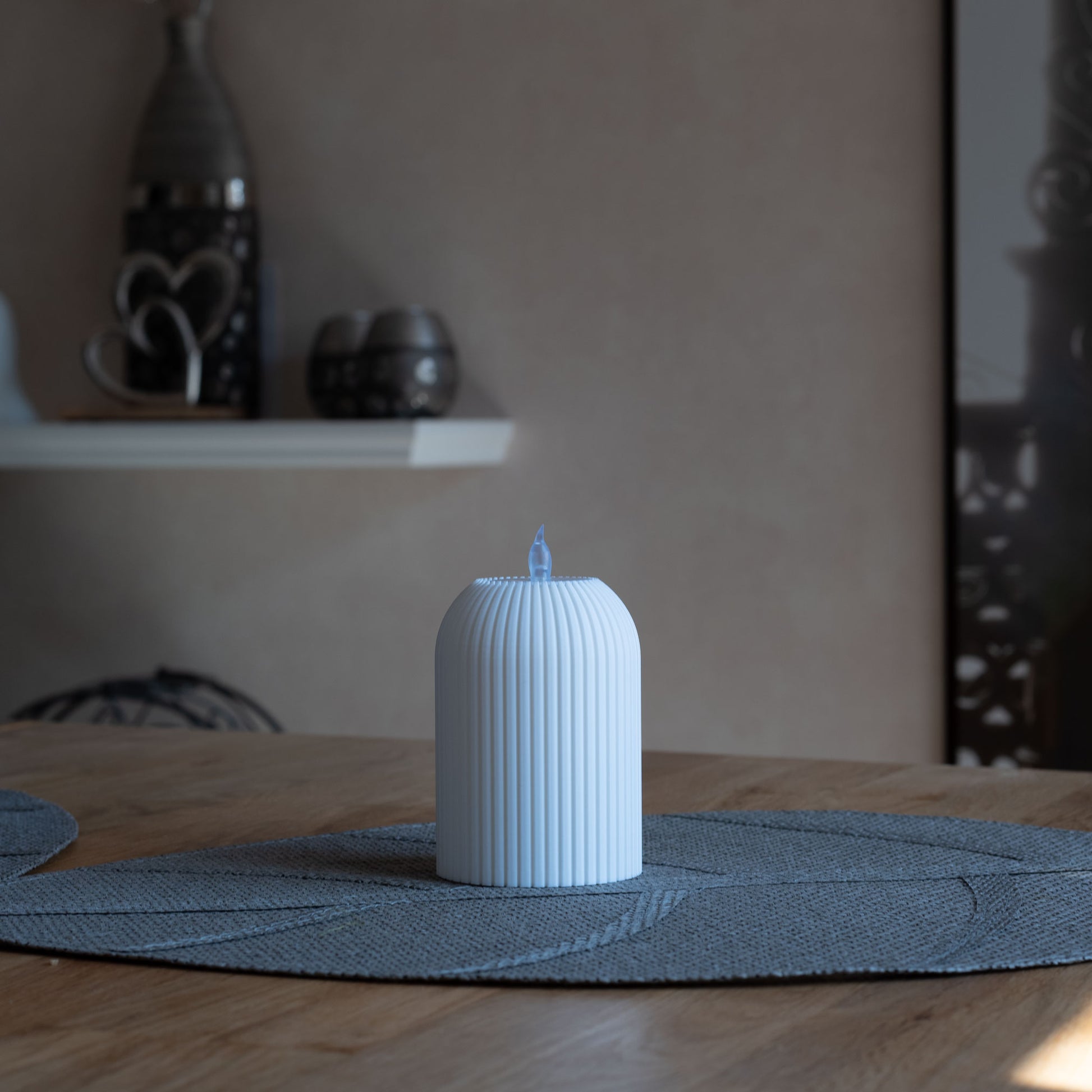 Nachhaltiges, weißes Teelicht mit vertikalen Rillen, 3D-gedruckt aus PLA, steht auf grauem Tischset