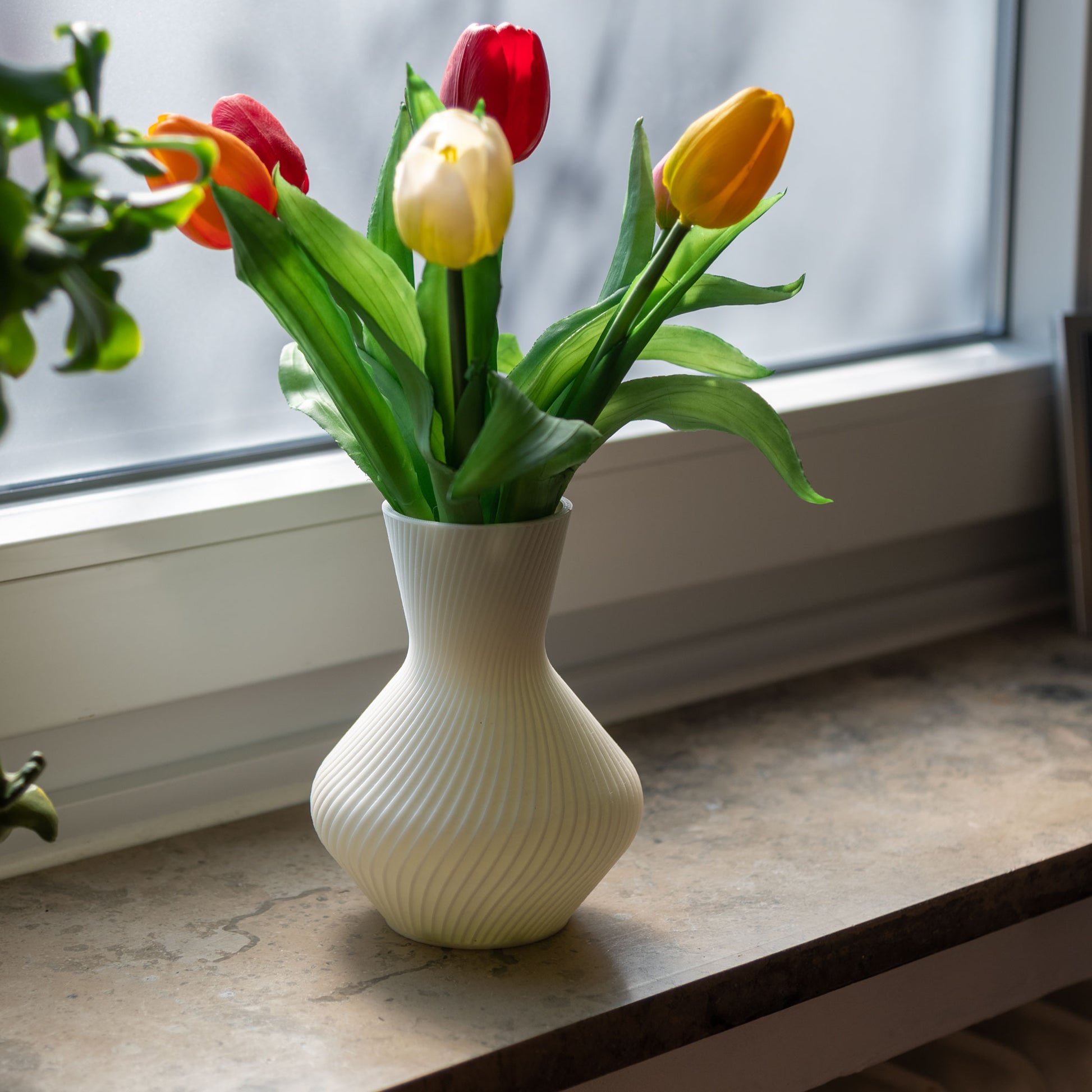 Weiße Vase Line aus PLA mit gerillter Oberfläche, 3D-gedruckt, mit roten, gelben und weißen Tulpen auf Fensterbank